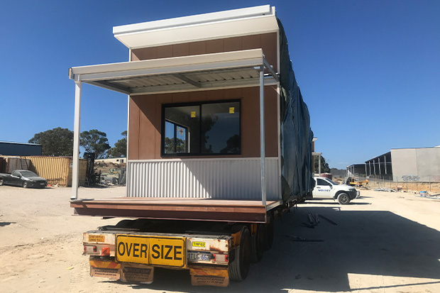 Truck carrying a Rapid Modular WA portable building along a highway in Western Australia