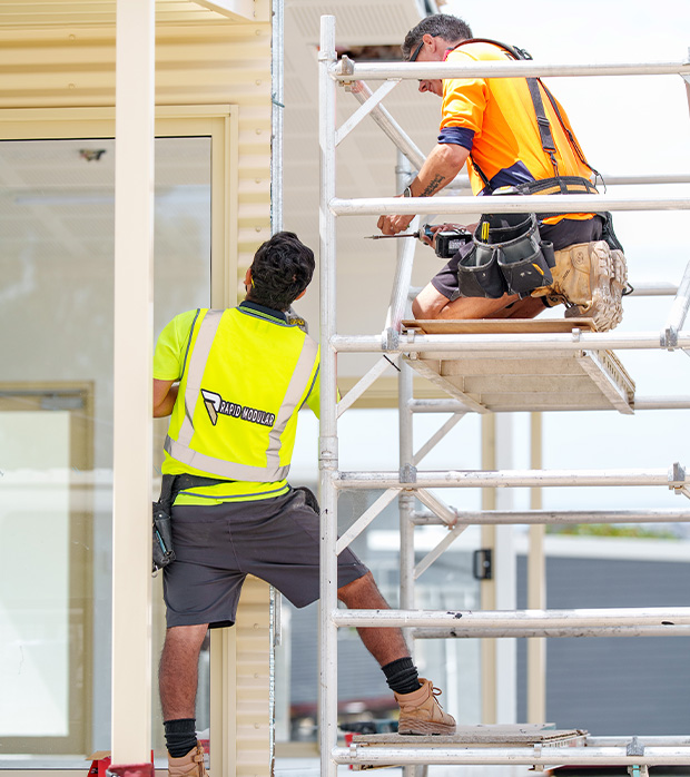 Two Rapid Modular WA workers assembling a modular building at the construction yard